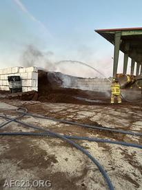 Crews extinguishing flares up at the top of the mulch pile 